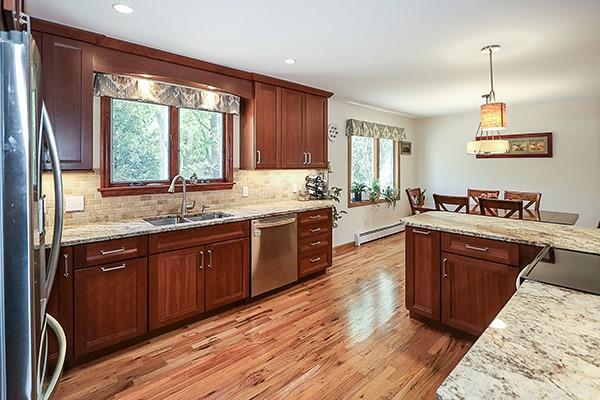 kitchen with decorative backsplash, a sink, light wood-style flooring, hanging light fixtures, and stainless steel appliances