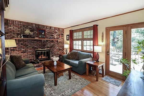 living area with crown molding, wood finished floors, and a fireplace