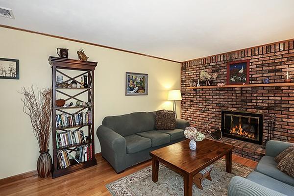 living room with visible vents, crown molding, wood finished floors, a fireplace, and baseboards