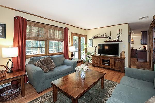 living area featuring visible vents, ornamental molding, and wood finished floors