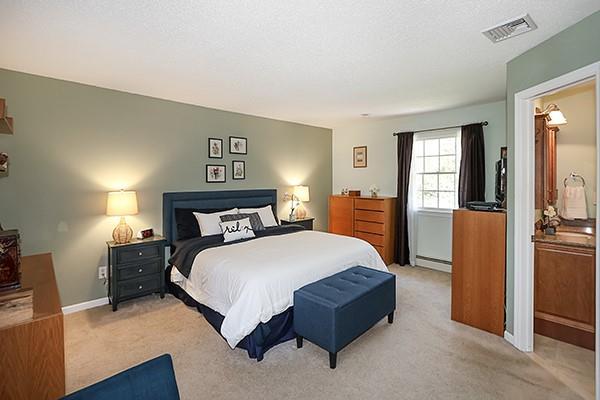 carpeted bedroom featuring visible vents, baseboards, and baseboard heating