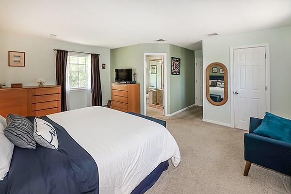 bedroom featuring light colored carpet, baseboards, ensuite bath, and visible vents