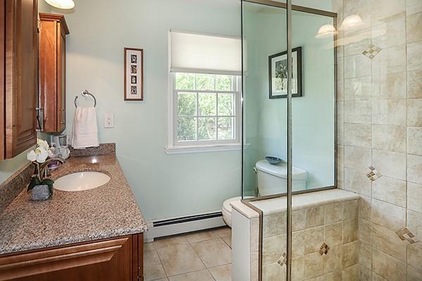 bathroom featuring tile patterned flooring, a baseboard radiator, vanity, and tiled shower