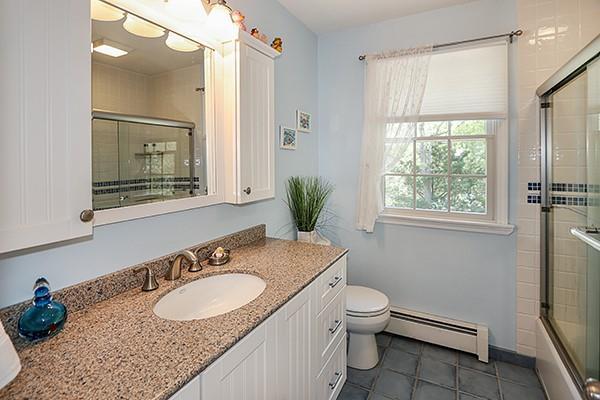 full bathroom with tile patterned flooring, vanity, toilet, combined bath / shower with glass door, and a baseboard heating unit