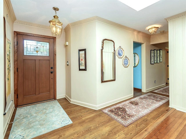 entrance foyer featuring baseboards, a notable chandelier, ornamental molding, and wood finished floors