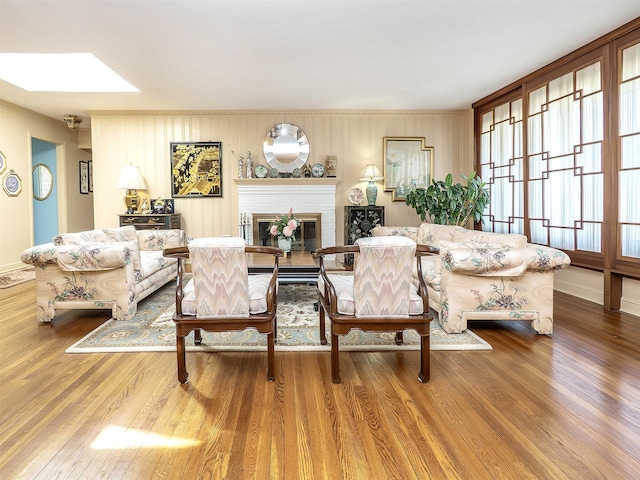 living area with a skylight, baseboards, ornamental molding, and wood finished floors
