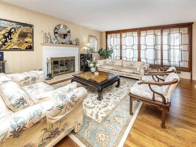 living area featuring crown molding, wood finished floors, and a fireplace