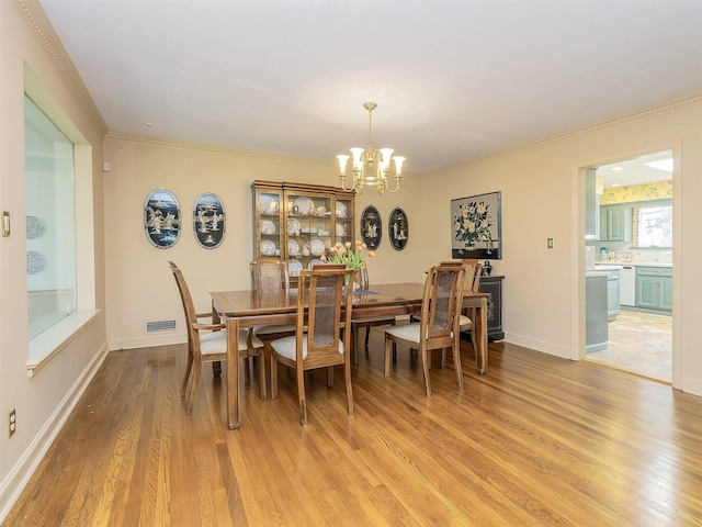dining area featuring visible vents, crown molding, baseboards, light wood-style flooring, and a notable chandelier