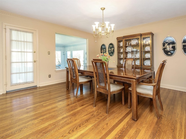 dining space featuring baseboards, a notable chandelier, ornamental molding, and light wood-style flooring