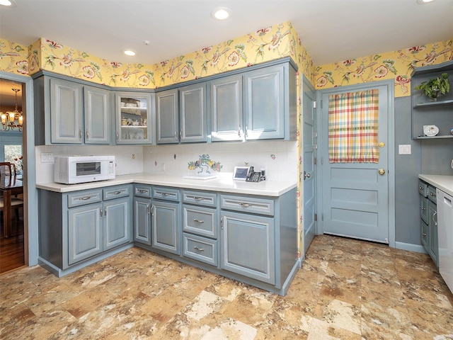 kitchen featuring gray cabinetry, light countertops, white microwave, and wallpapered walls
