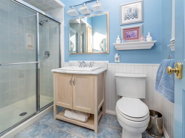 bathroom with wainscoting, vanity, a shower stall, and toilet