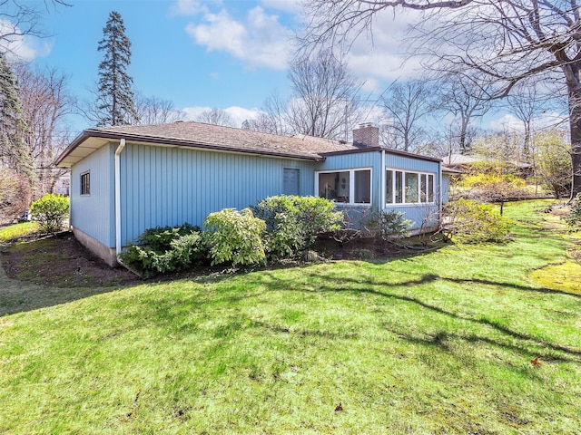 view of side of home featuring a lawn and a chimney