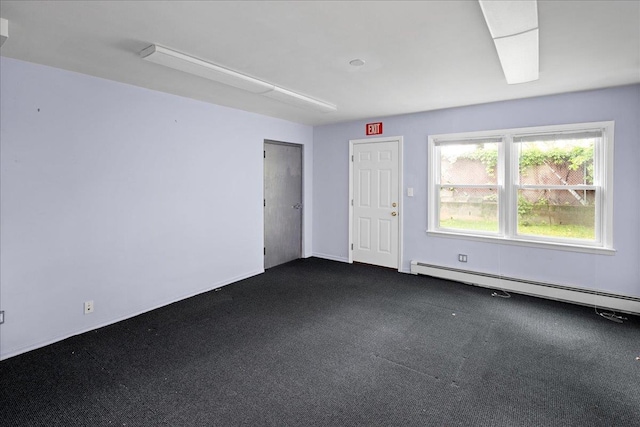 spare room with baseboard heating and dark colored carpet