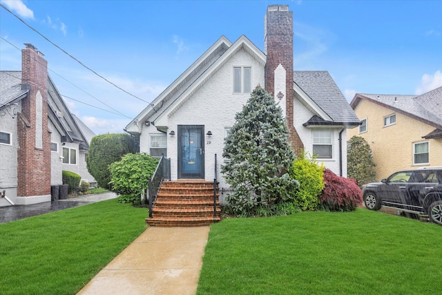 view of front facade featuring a front lawn, a chimney, and central AC unit