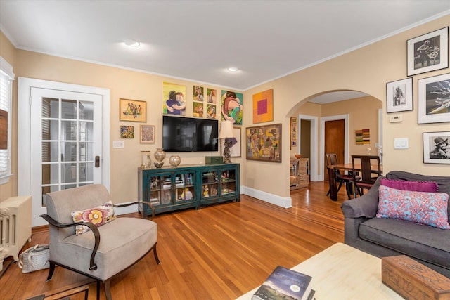 living room featuring arched walkways, wood finished floors, ornamental molding, baseboards, and recessed lighting