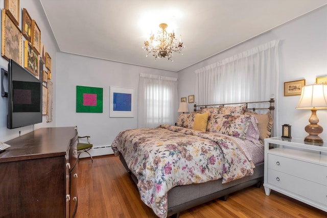 bedroom with baseboard heating, a chandelier, and wood finished floors