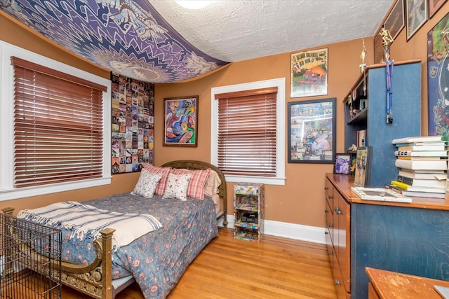 bedroom featuring wood finished floors, baseboards, and a textured ceiling