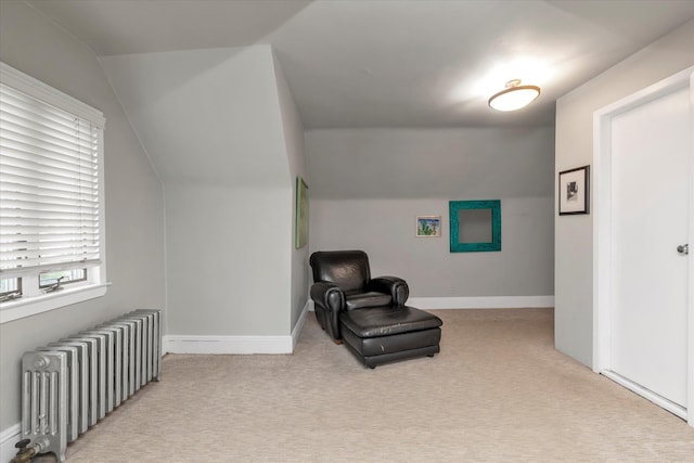 sitting room with radiator, vaulted ceiling, carpet flooring, and baseboards