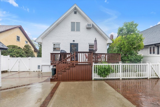 back of property featuring a gate, a patio area, a deck, and a wall mounted air conditioner