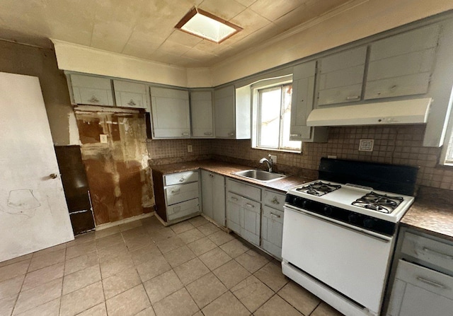 73 4th St, Brentwood, NY 11717 - kitchen with decorative backsplash, gas range gas stove, a sink, gray cabinetry, and under cabinet range hood