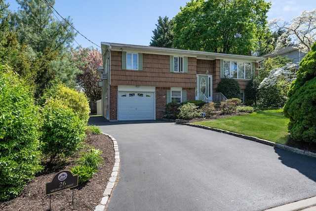 split foyer home with brick siding, a garage, a front lawn, and driveway