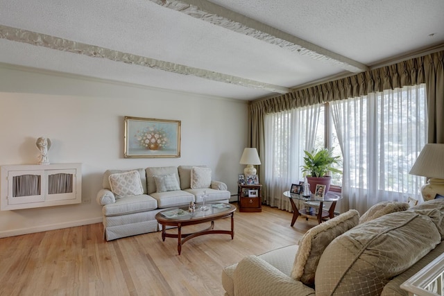 living area featuring baseboards, light wood-style flooring, and a textured ceiling