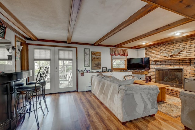 living area featuring wood finished floors, a baseboard heating unit, a wealth of natural light, and a fireplace