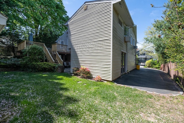 view of property exterior featuring a wooden deck, fence, a patio area, a yard, and stairway