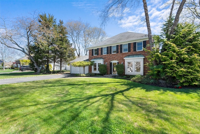 view of front facade featuring french doors, a front yard, a garage, brick siding, and aphalt driveway