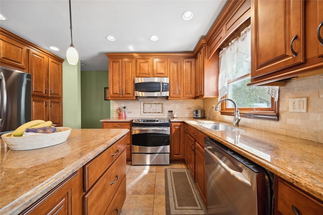 kitchen featuring backsplash, appliances with stainless steel finishes, brown cabinetry, and a sink