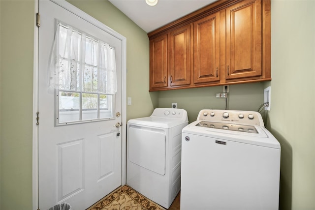 clothes washing area with separate washer and dryer and cabinet space