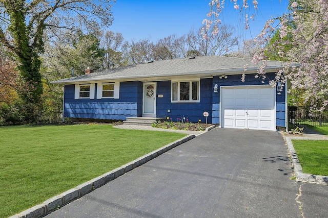 single story home with a front lawn, a garage, a shingled roof, driveway, and a chimney