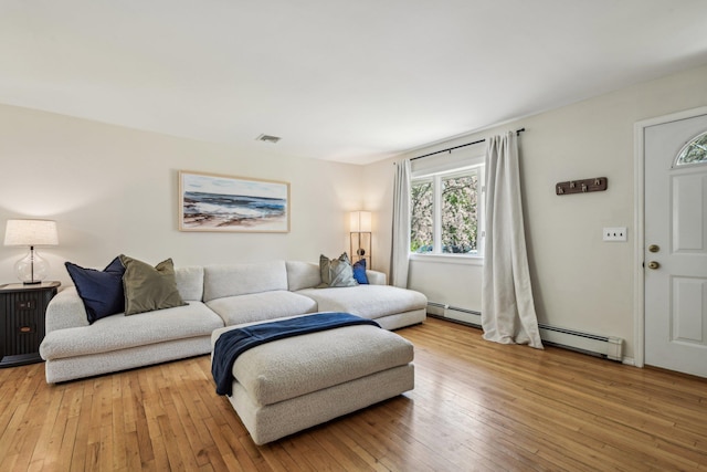 living room with light wood finished floors, visible vents, and baseboard heating