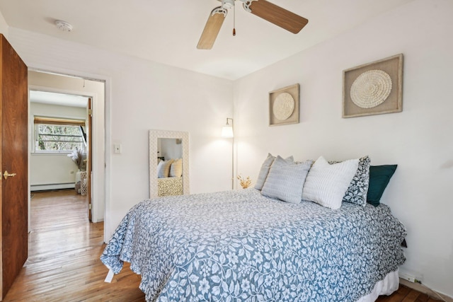 bedroom with wood finished floors, a ceiling fan, and a baseboard radiator