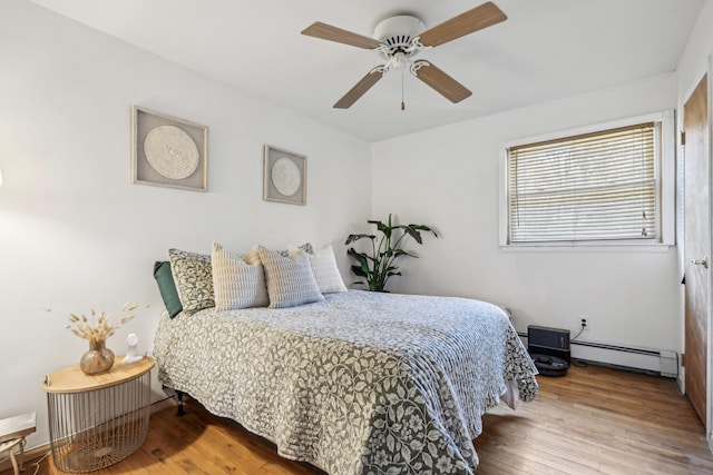 bedroom with a baseboard heating unit, hardwood / wood-style floors, and ceiling fan