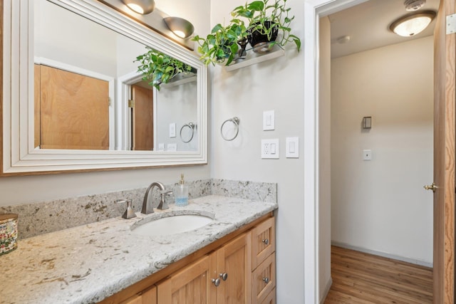 bathroom with vanity, wood finished floors, and baseboards