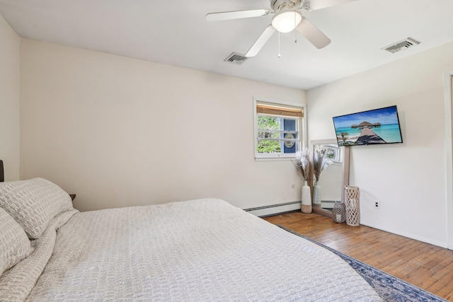 bedroom featuring a baseboard heating unit, visible vents, and hardwood / wood-style flooring