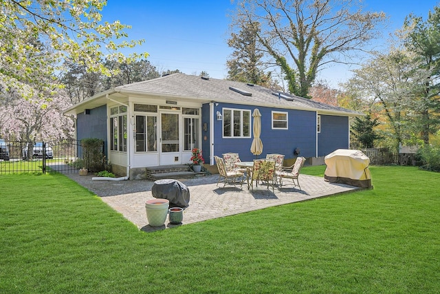 back of property with a sunroom, a patio, a yard, roof with shingles, and fence