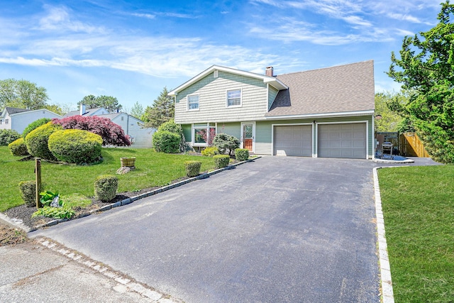 view of front of house featuring an attached garage, asphalt driveway, roof with shingles, and a chimney