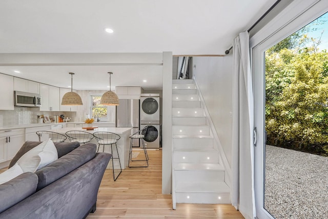 stairs featuring stacked washing machine and dryer, wood finished floors, and recessed lighting