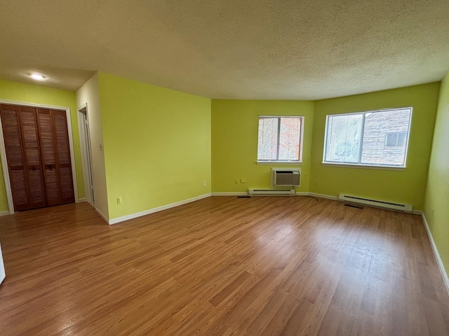 spare room with baseboards, a textured ceiling, a baseboard heating unit, and wood finished floors