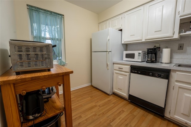 kitchen featuring white appliances, light countertops, white cabinets, and light wood-style floors