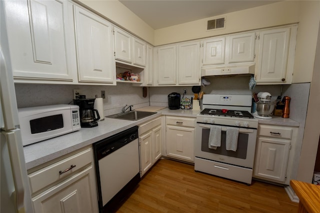 kitchen featuring visible vents, white appliances, light countertops, under cabinet range hood, and a sink