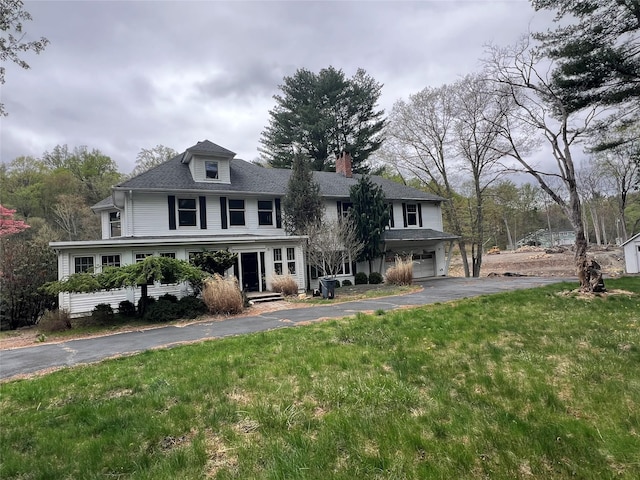 view of front of property with driveway, a chimney, a front yard, and a garage