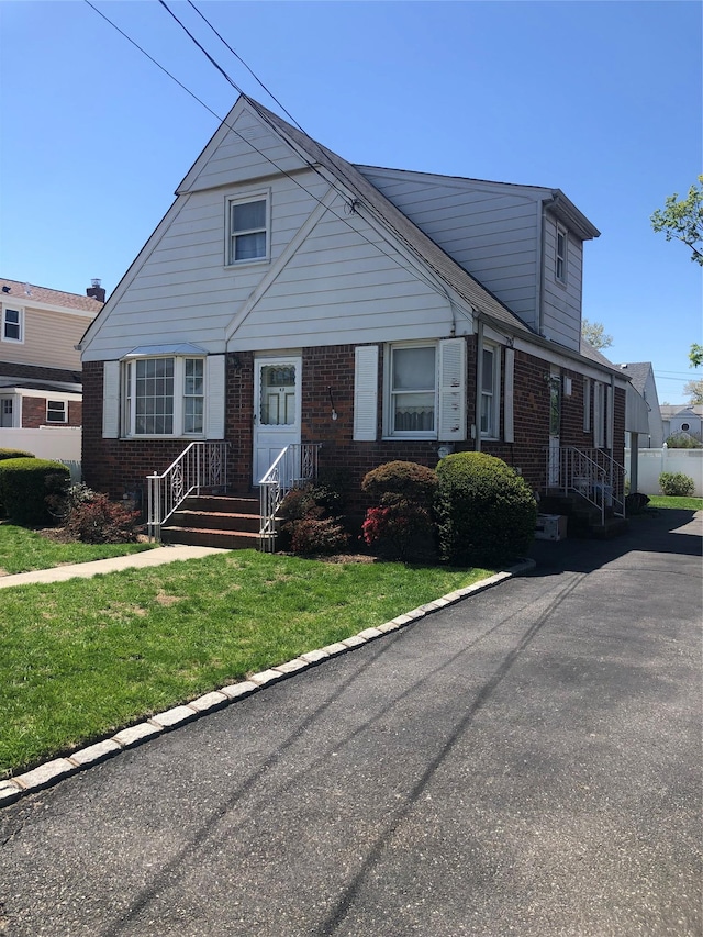 bungalow featuring a front lawn and brick siding