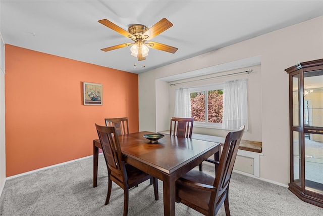 dining room featuring ceiling fan, light carpet, and baseboards