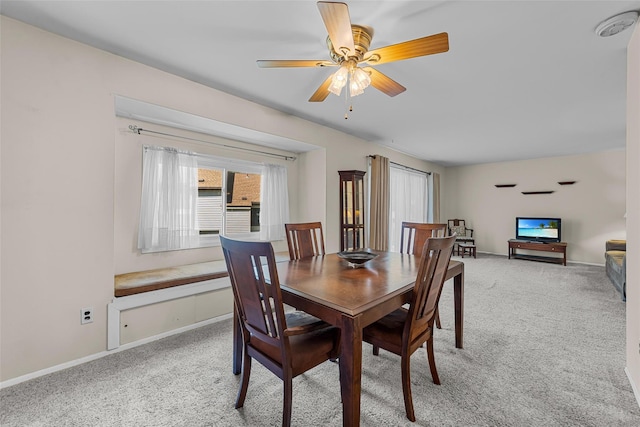 dining area featuring baseboards, ceiling fan, and light colored carpet