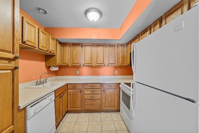 kitchen with light tile patterned flooring, white appliances, light countertops, brown cabinets, and a sink