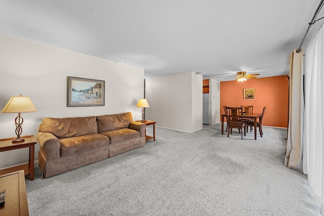 carpeted living area with baseboards and a ceiling fan