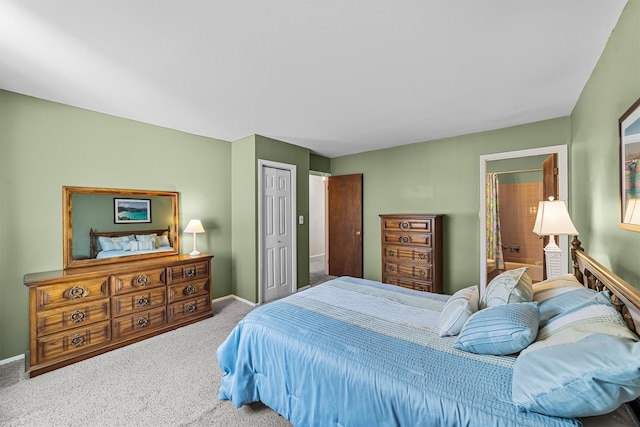 carpeted bedroom featuring a closet, baseboards, and ensuite bathroom